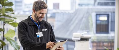 Un technicien sur sa tablette fini l'installation d'une imprimante Brother