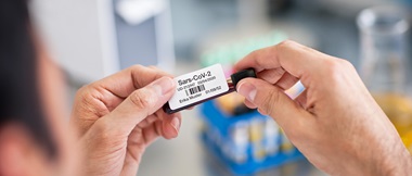 Un professionnel de la santé applique une étiquette adhésive provenant d'une imprimante d'étiquettes sur un échantillon médical.