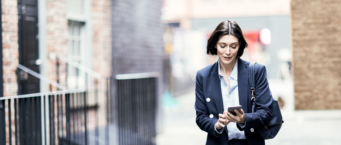 Femme marchant dans la rue et regardant son smartphone