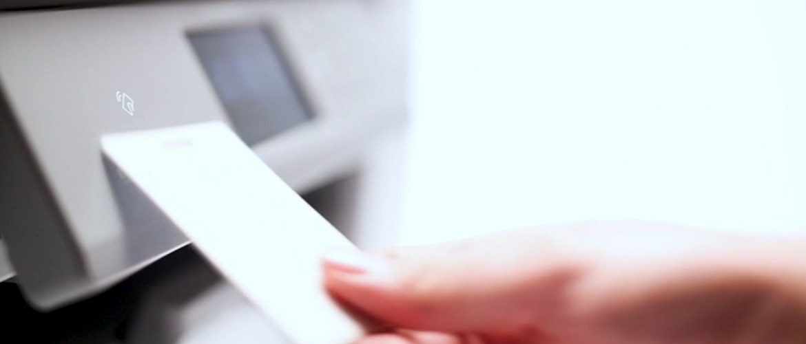Un membre du personnel de bureau tape une carte NFC (Near Field Communications) sur une imprimante à jet d'encre professionnelle Brother X-Series pour accéder aux fonctions d'impression et débloquer l'impression sécurisée. 