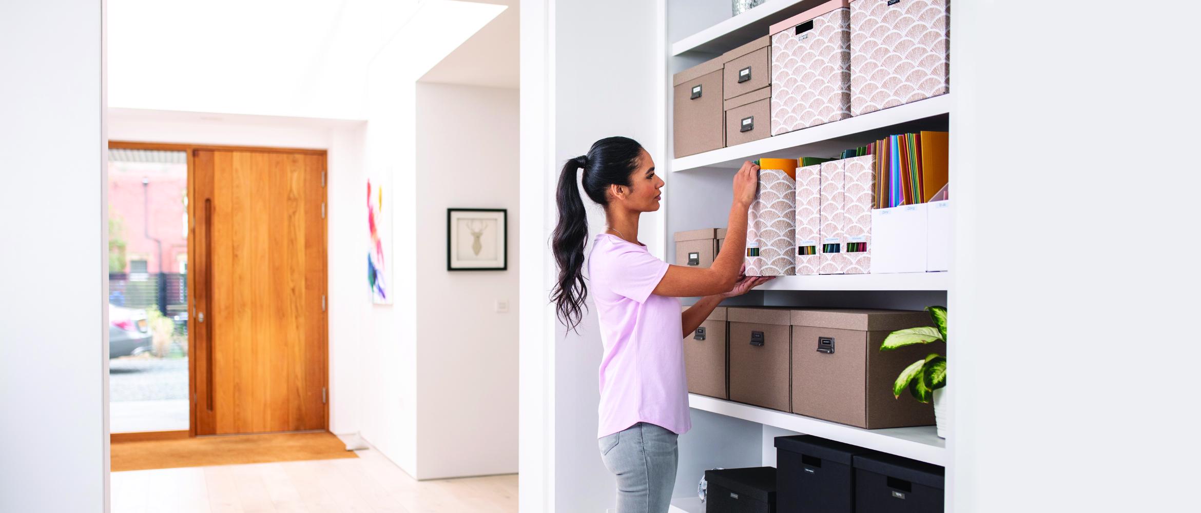 Une employée travaille depuis son bureau à domicile. Elle organise ses dossiers papiers à l'aide d'une imprimante d'étiquettes afin de contribuer à la productivité de l'entreprise.