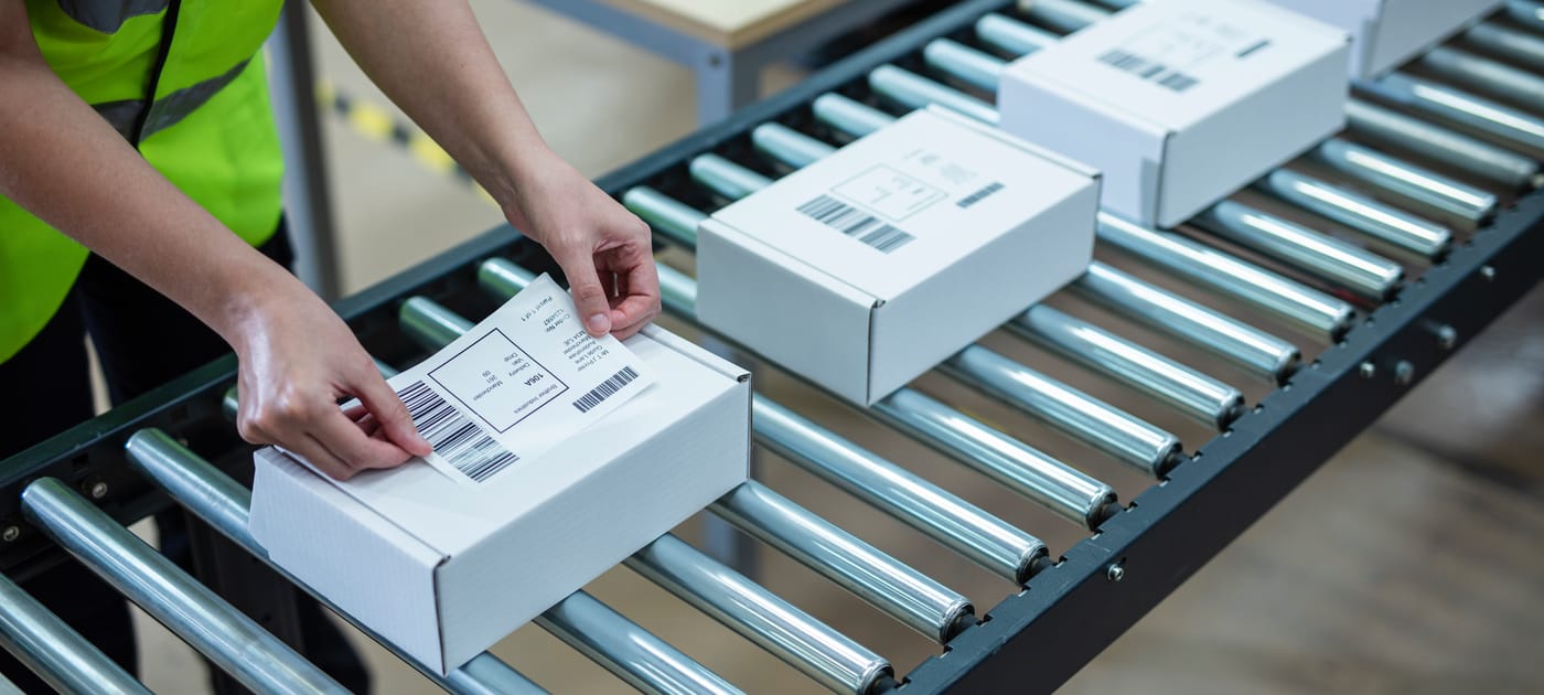 Personne déposant une étiquette autocollante sur une boite
