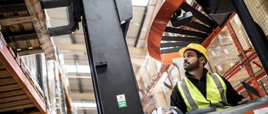 Sur cette image, un ouvrier conduit une nacelle dans un entrepôt 